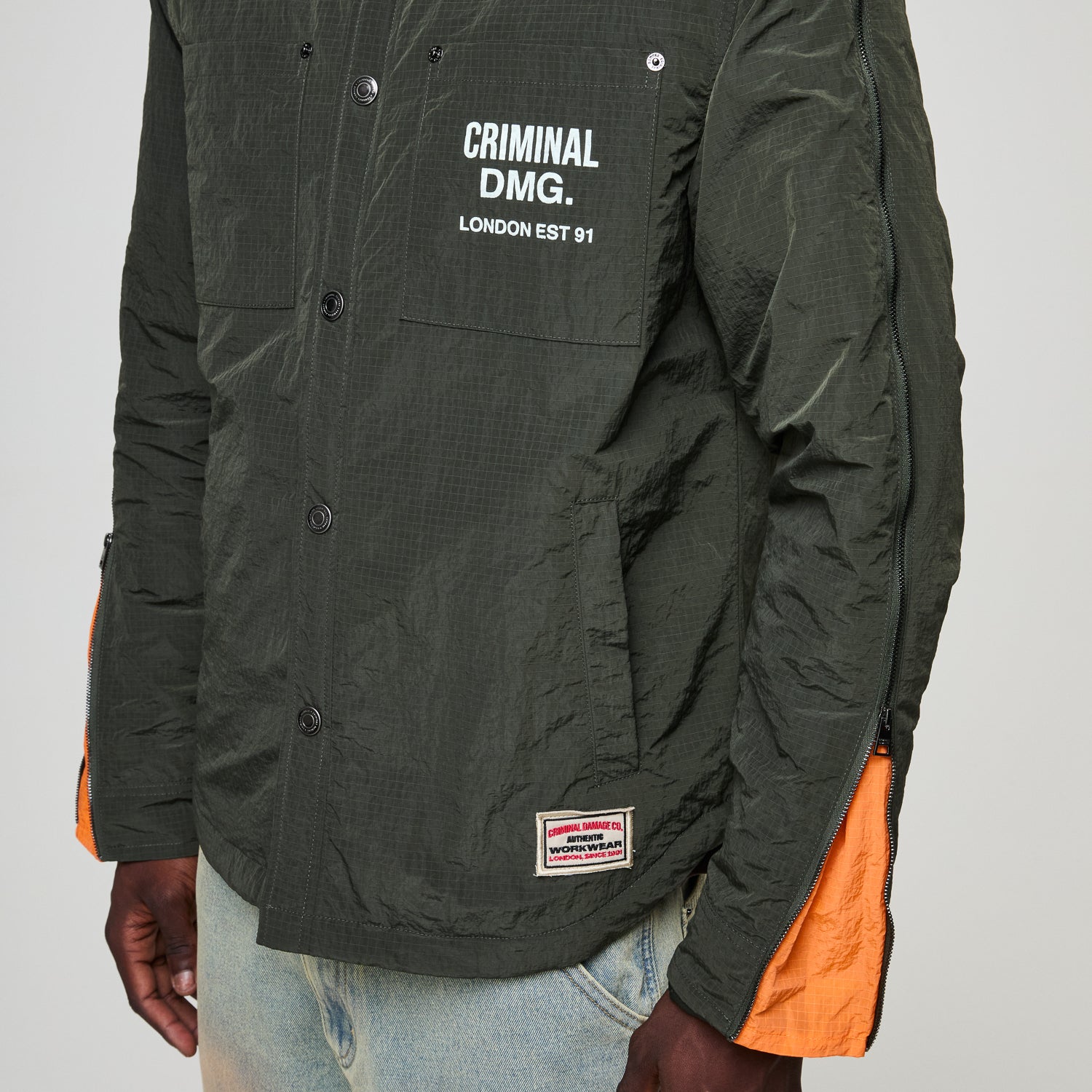 Black jacket with Criminal Damage  branding on a gray background