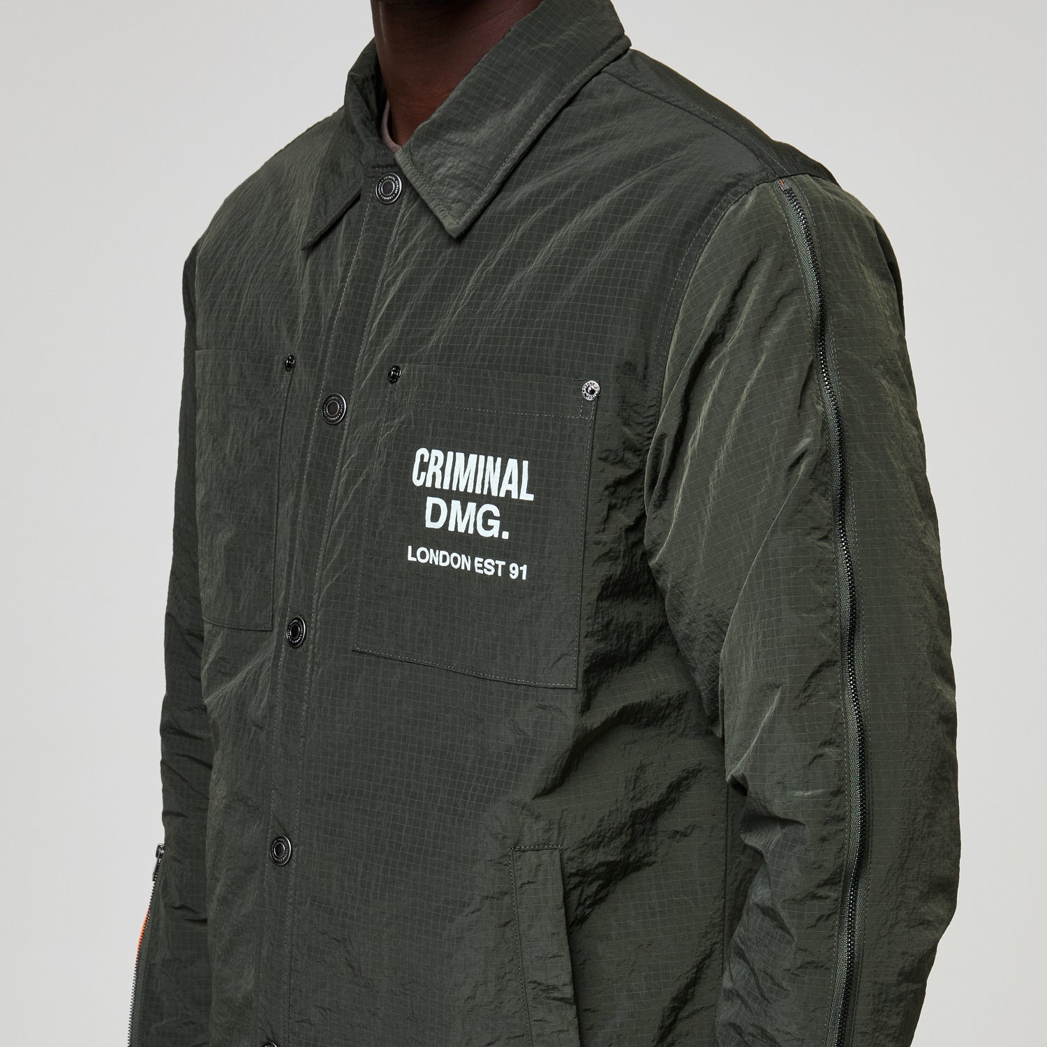 Dark green jacket with Criminal Damage text on a white background