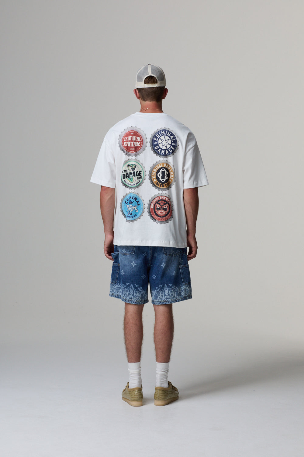 Model wearing a white t-shirt with colourful graphics on the back, standing against a plain background.