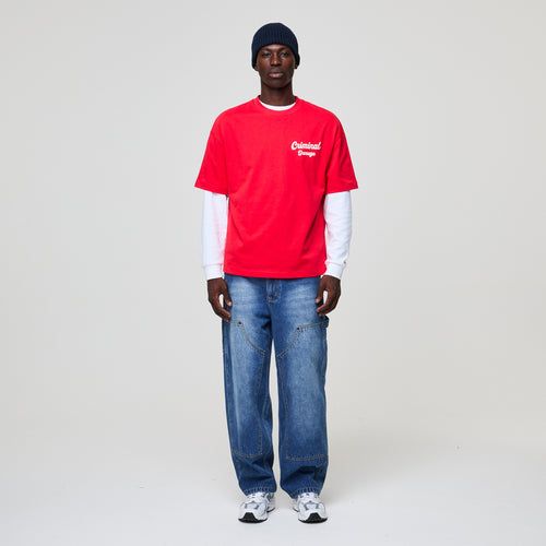 Person wearing a red shirt with a logo, blue jeans, and a black beanie on a white background