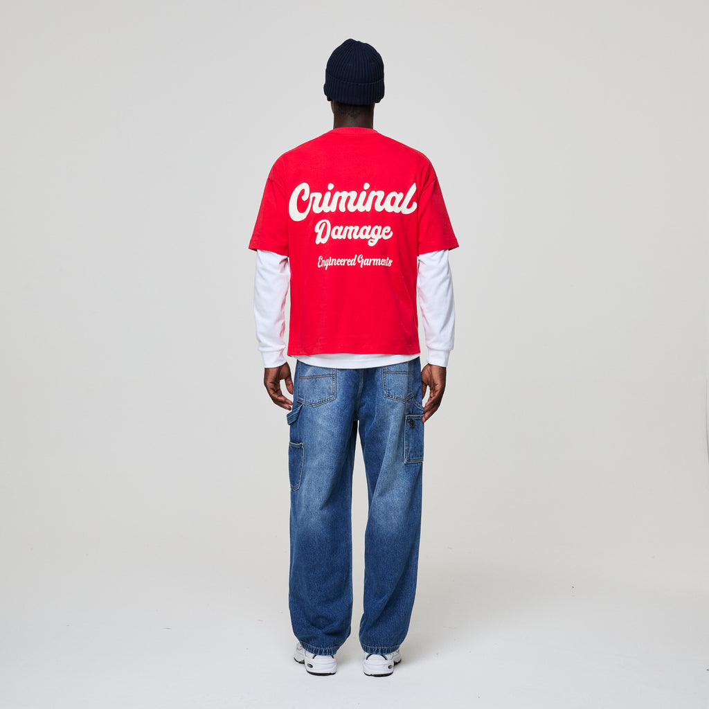 Person wearing a red 'Criminal Damage' shirt on a plain background