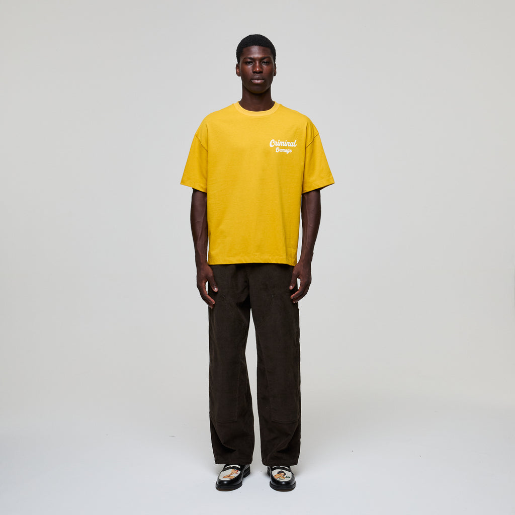 Person wearing a yellow t-shirt with text on a plain background