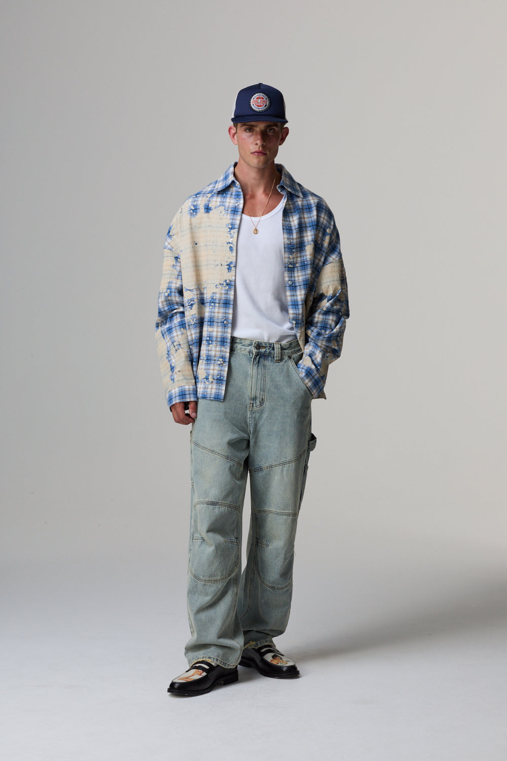 Model wearing a plaid Criminal Damage shirt on a grey background 