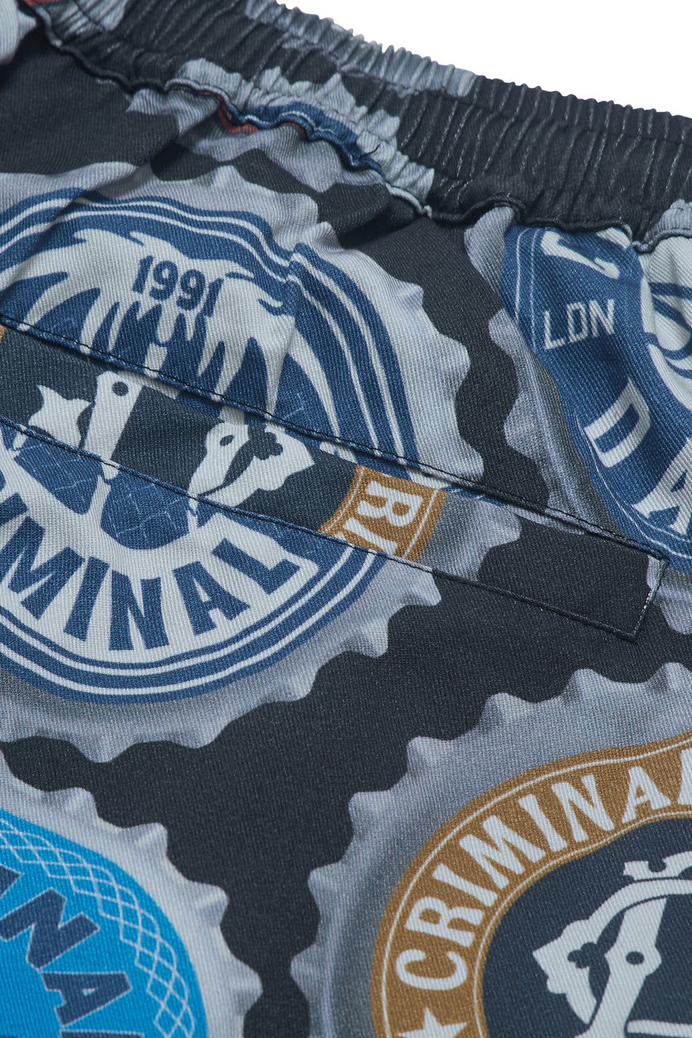 Close up of Criminal Damage shorts with bottle cap graphic 