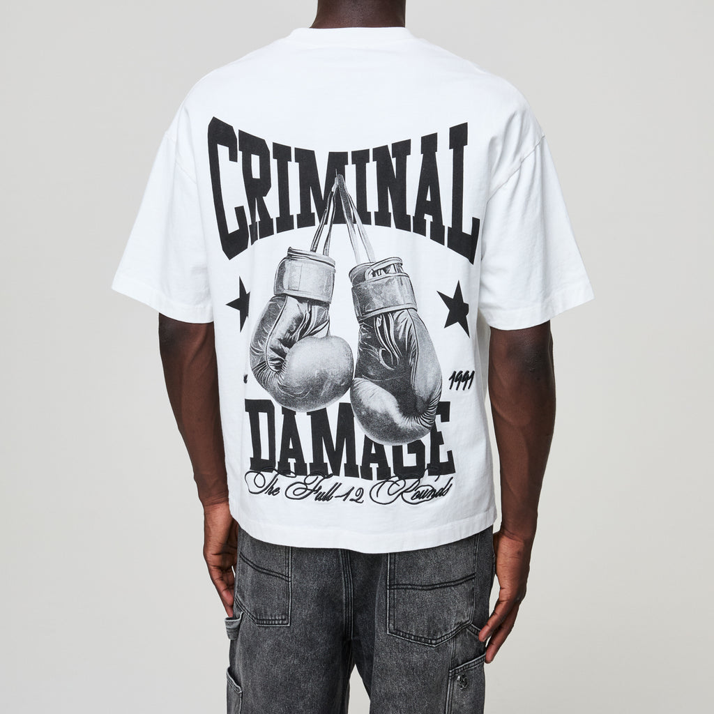 Person wearing a white t-shirt with boxing glove graphic and text on a plain background