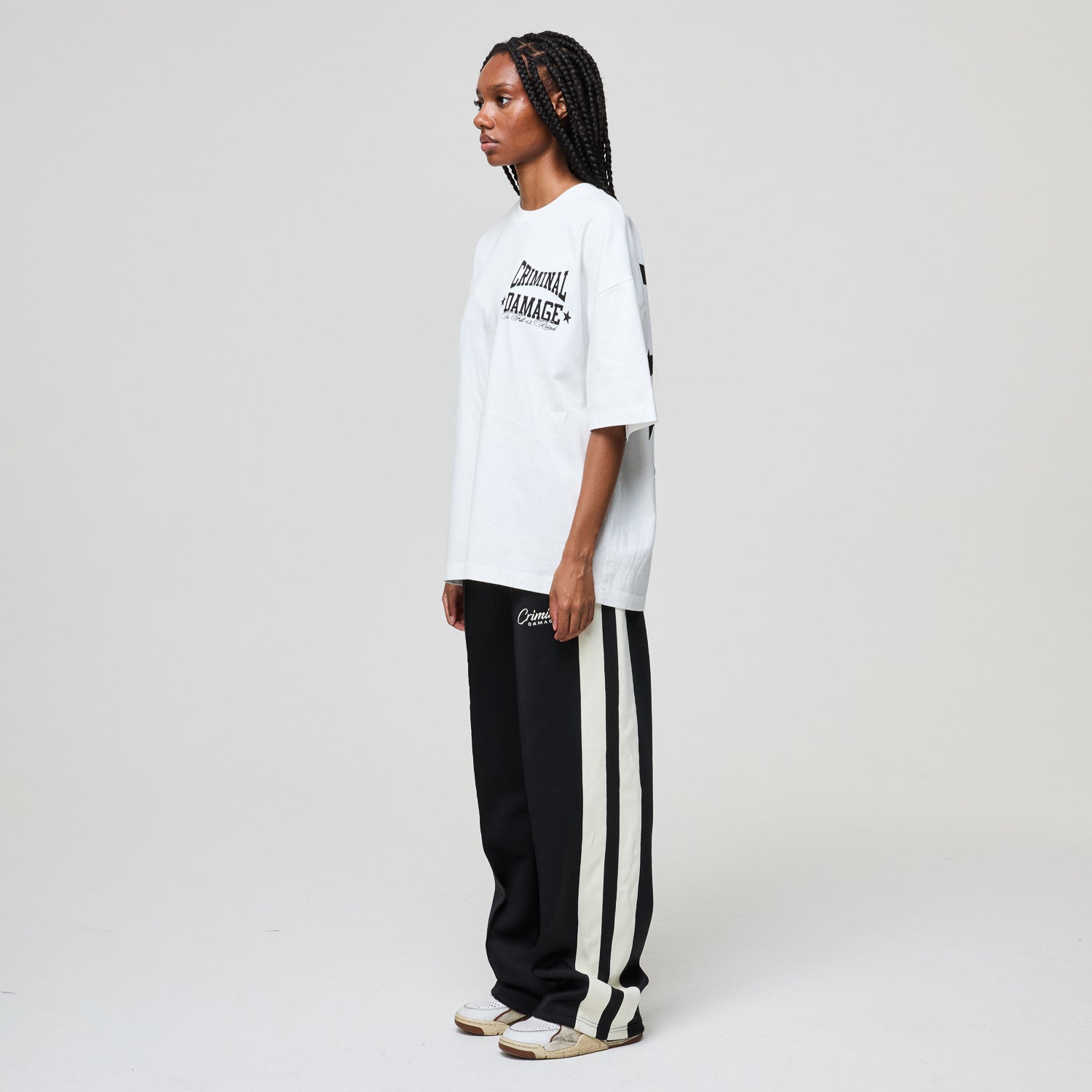 Person wearing a white t-shirt and black pants with white stripes on a plain background