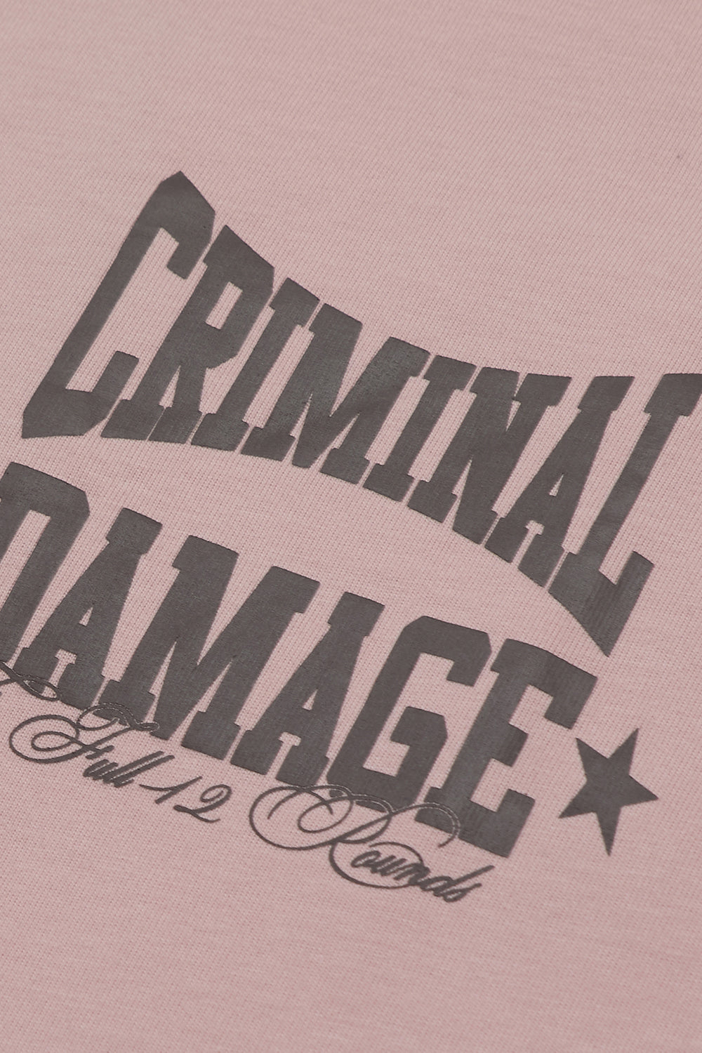 Close up of Criminal Damage logo on pink t-shirt