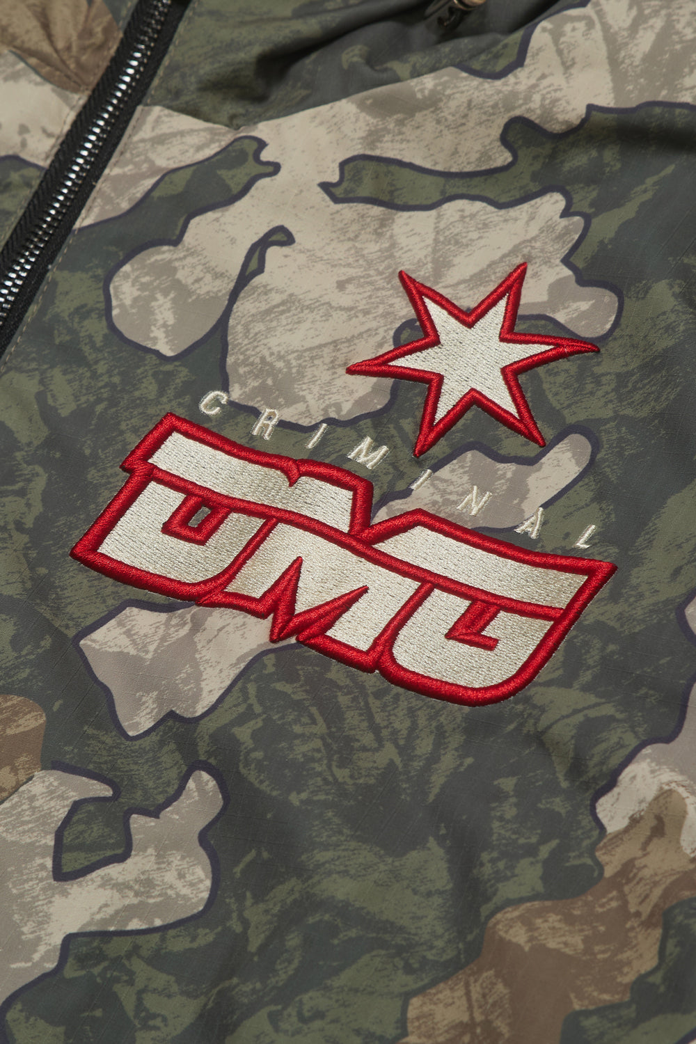 Close up of Criminal Damage embroidered patch on camo jacket