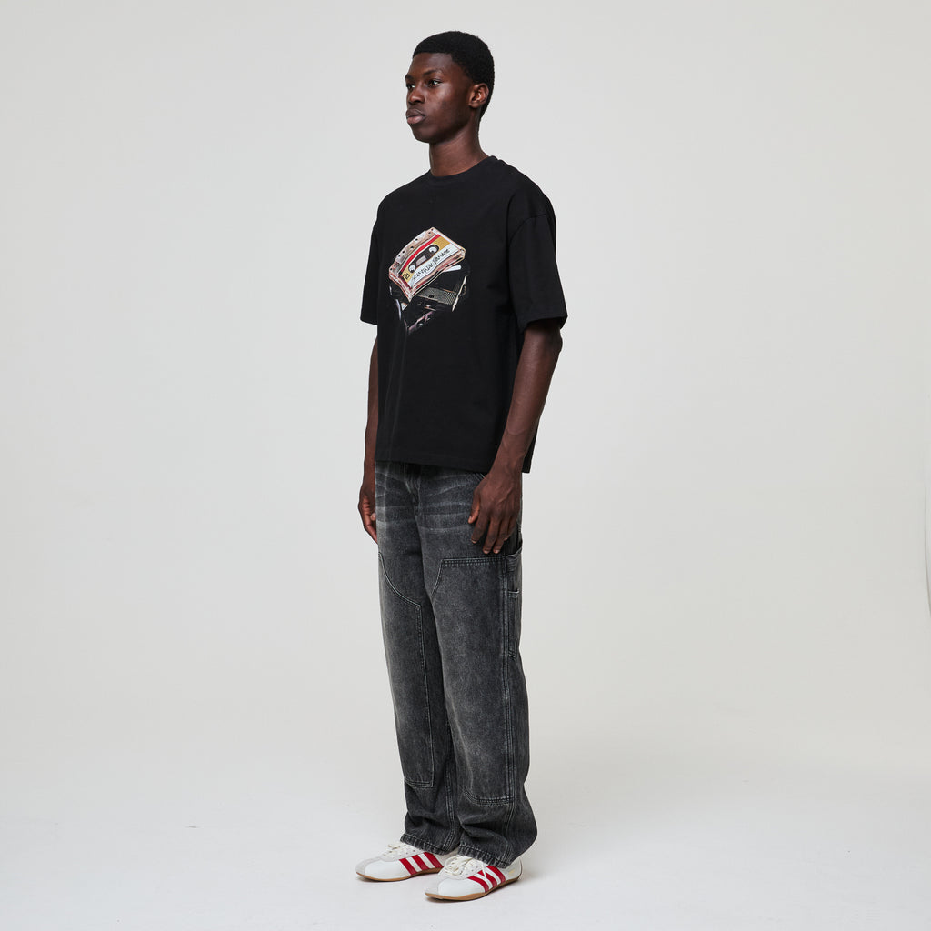 Person wearing a black Criminal Damage t-shirt with a graphic design on a white background