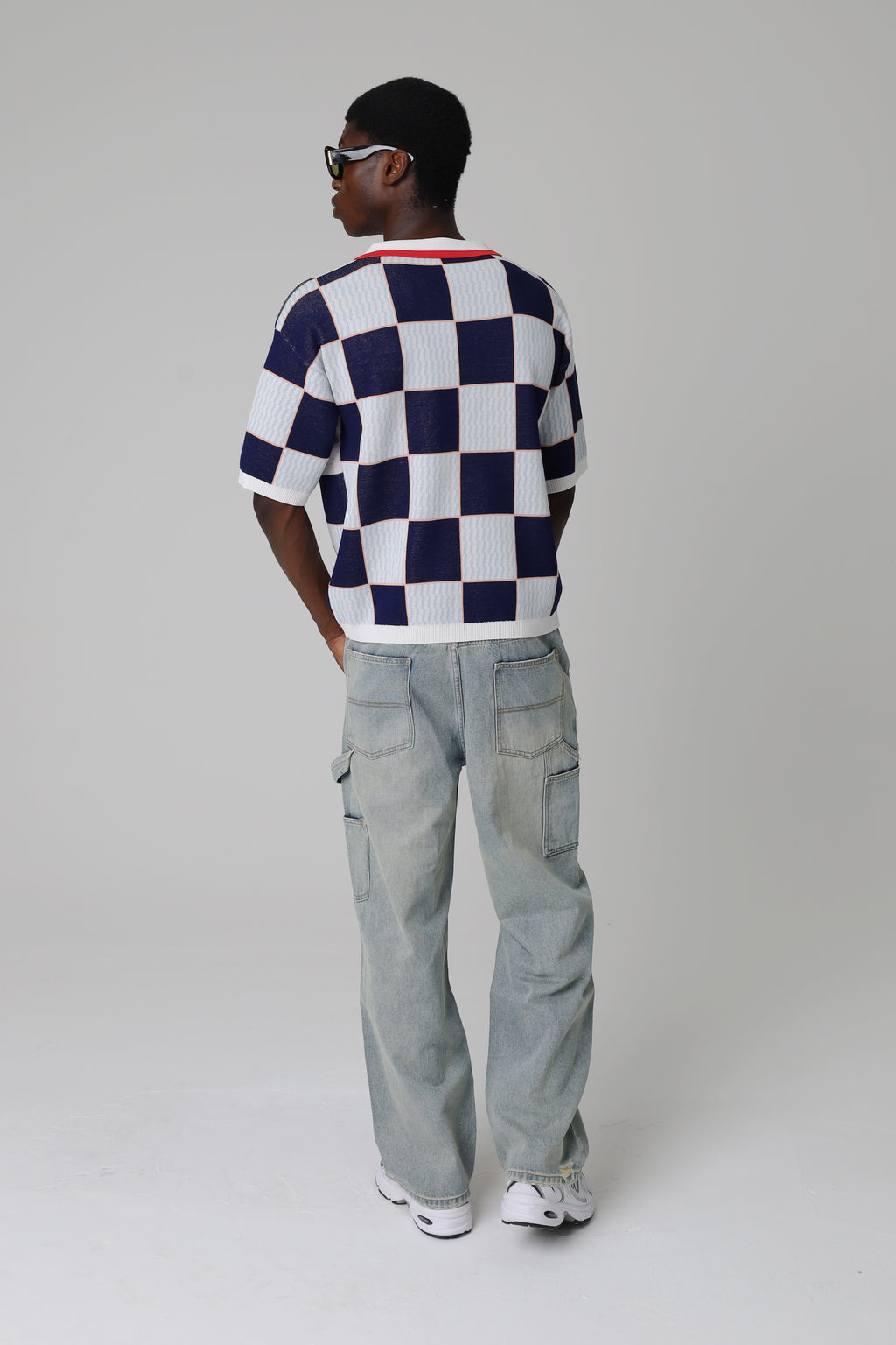Model wearing a Criminal Damage checkered shirt and light blue jeans on a grey background