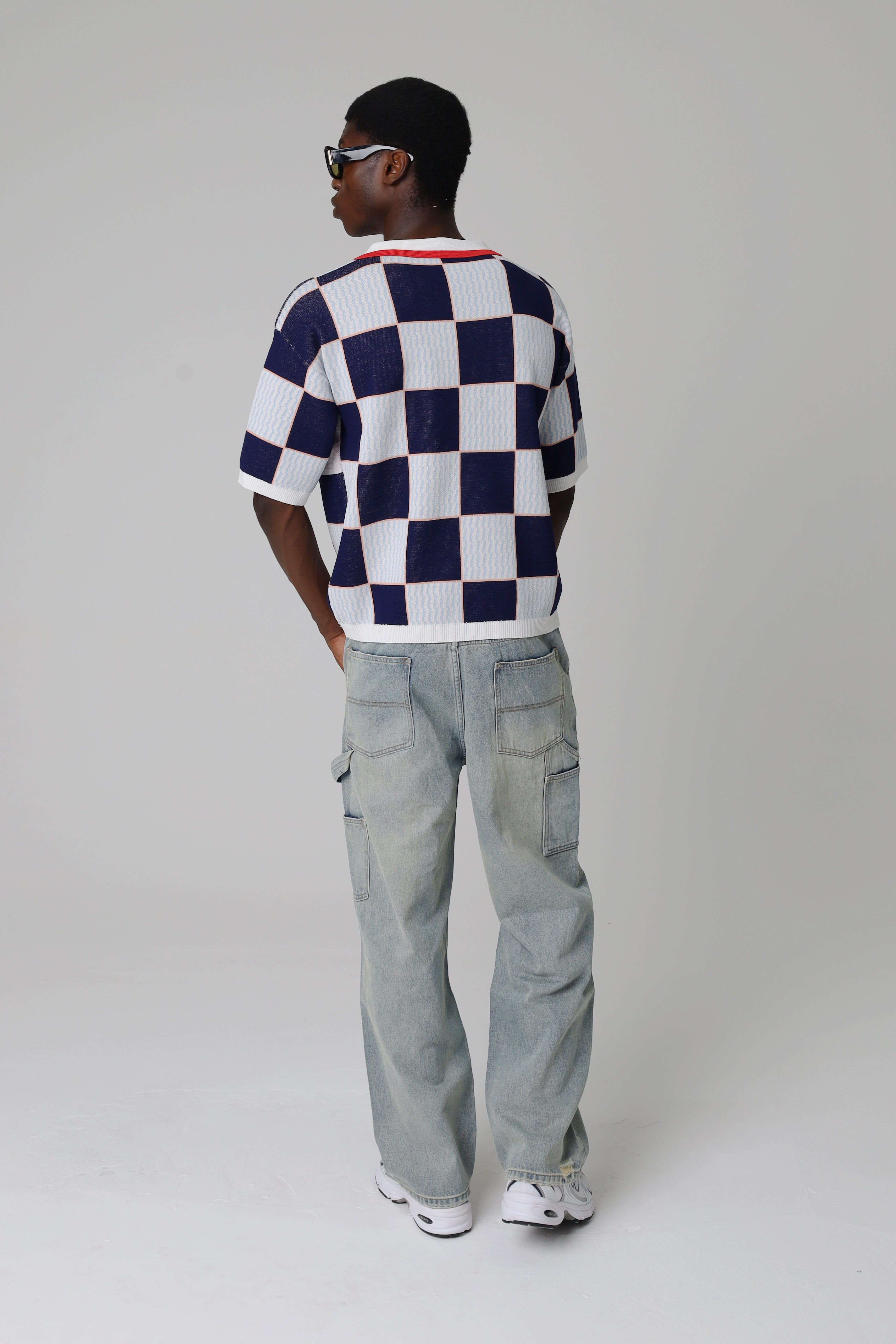 Model wearing a Criminal Damage checkered shirt and light blue jeans on a grey background