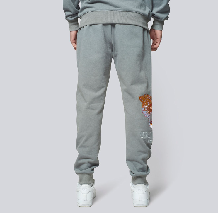 Model wearing grey sweatpants with a design on a plain background