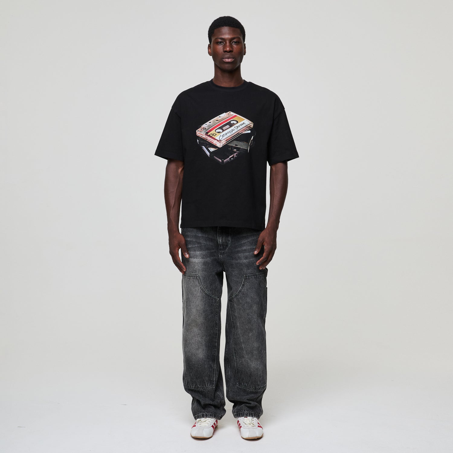 Person wearing a black Criminal Damage  t-shirt with a graphic design on a plain background