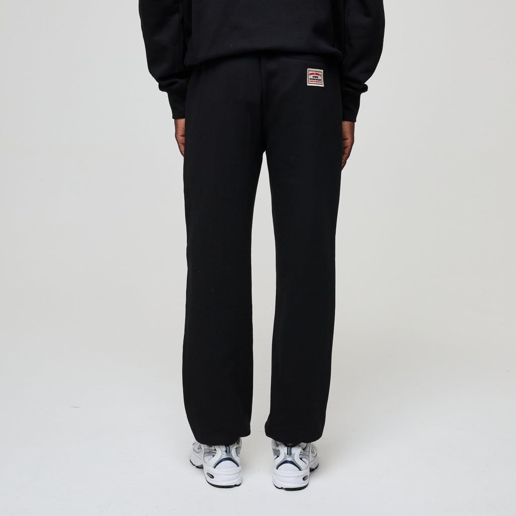 Person wearing black sweatpants with a brand logo on a white background