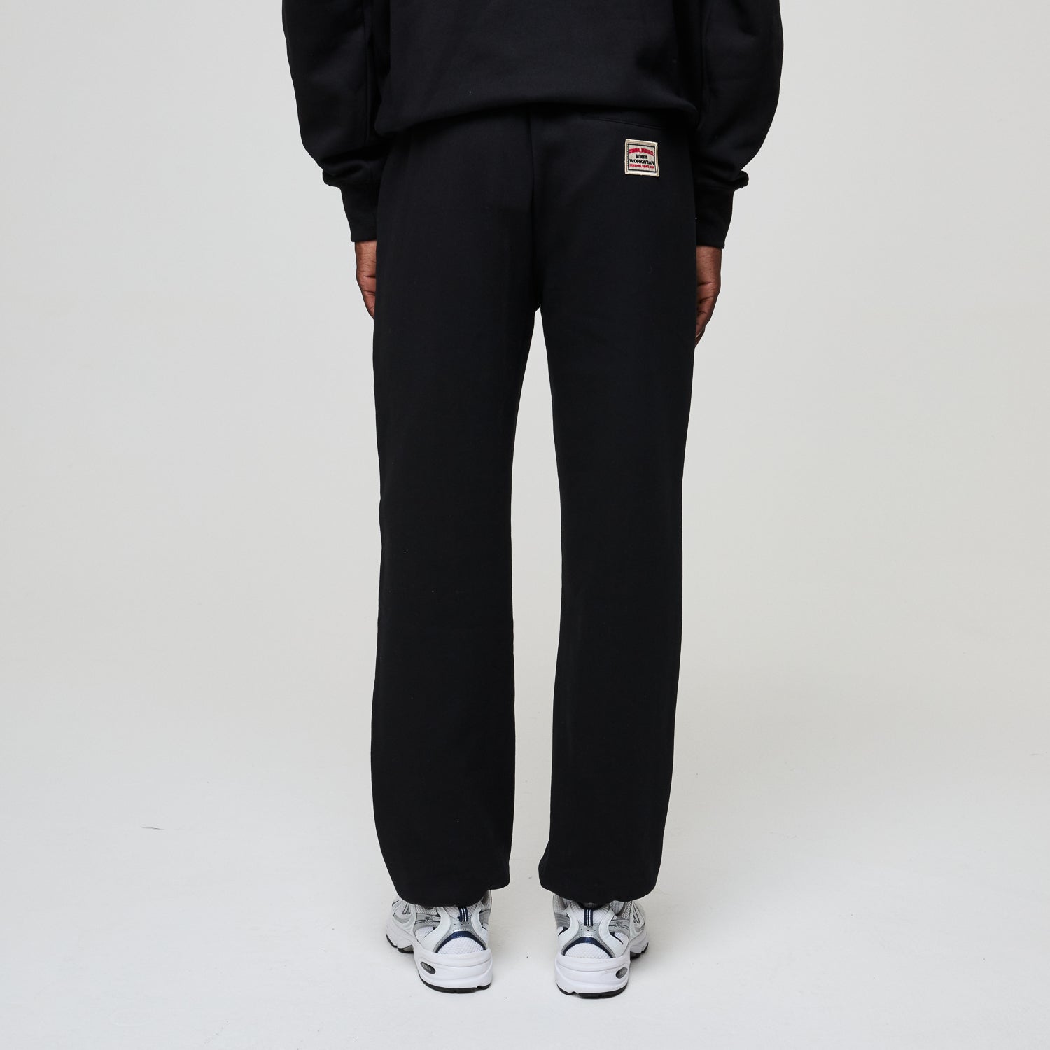 Person wearing black sweatpants with a brand logo on a white background