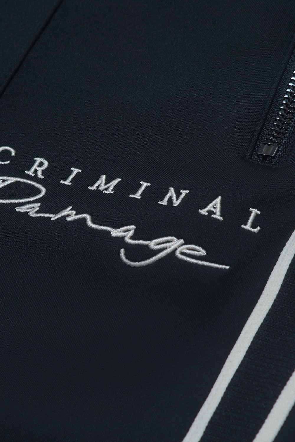 Close up of Criminal Damage logo on pants on white background