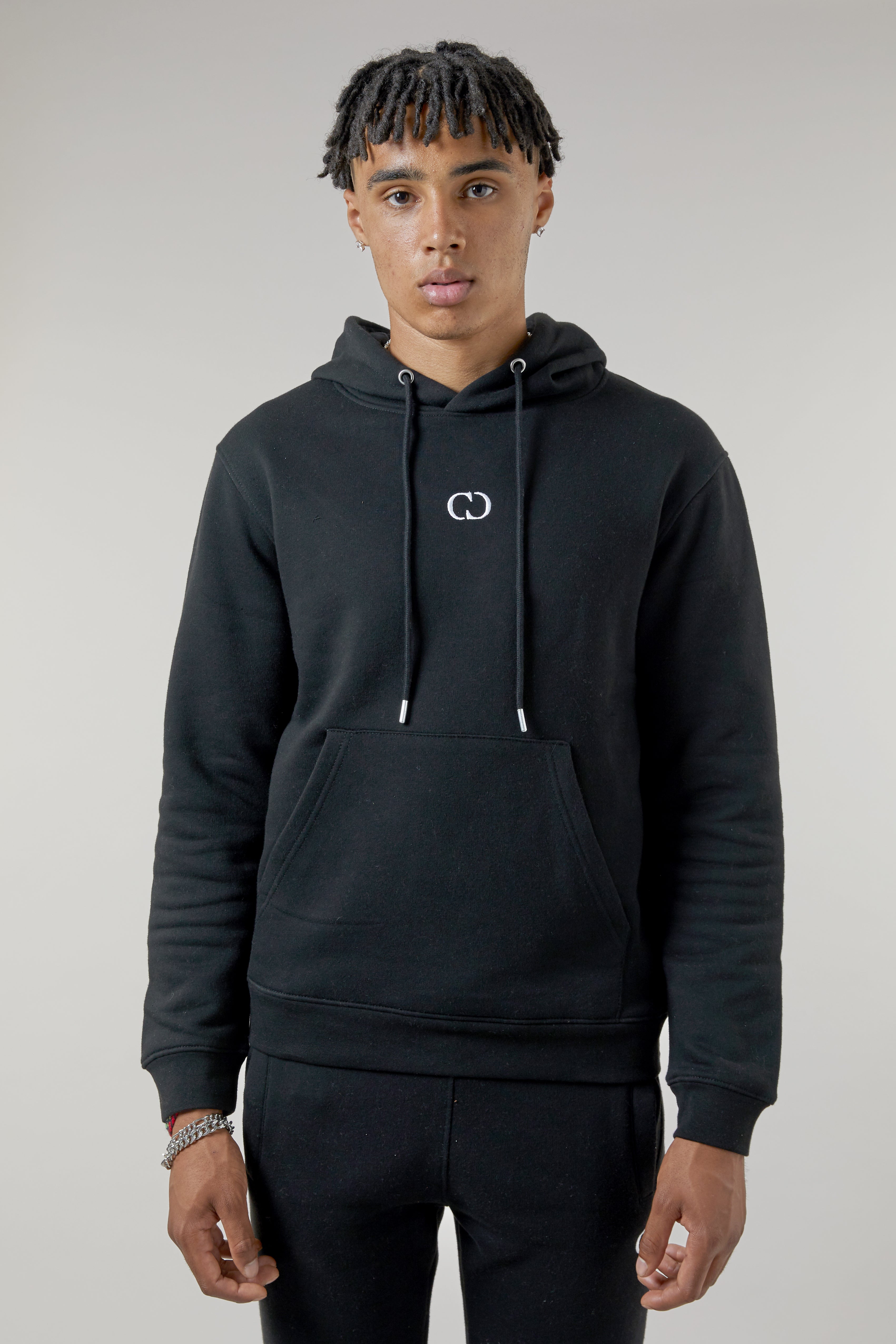 Man wearing a black hoodie with a logo on a plain background