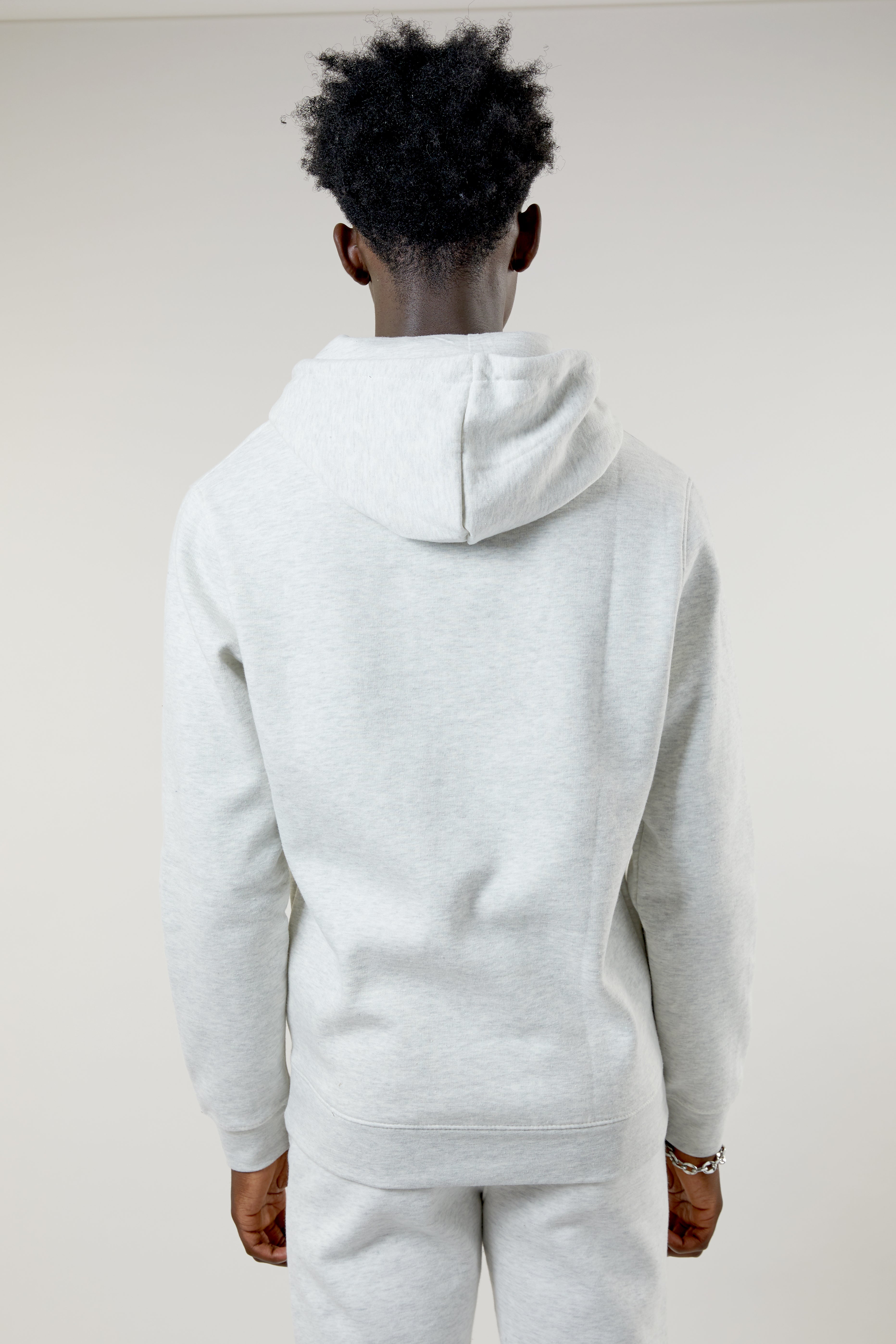 Person wearing a gray hoodie and pants against a white background