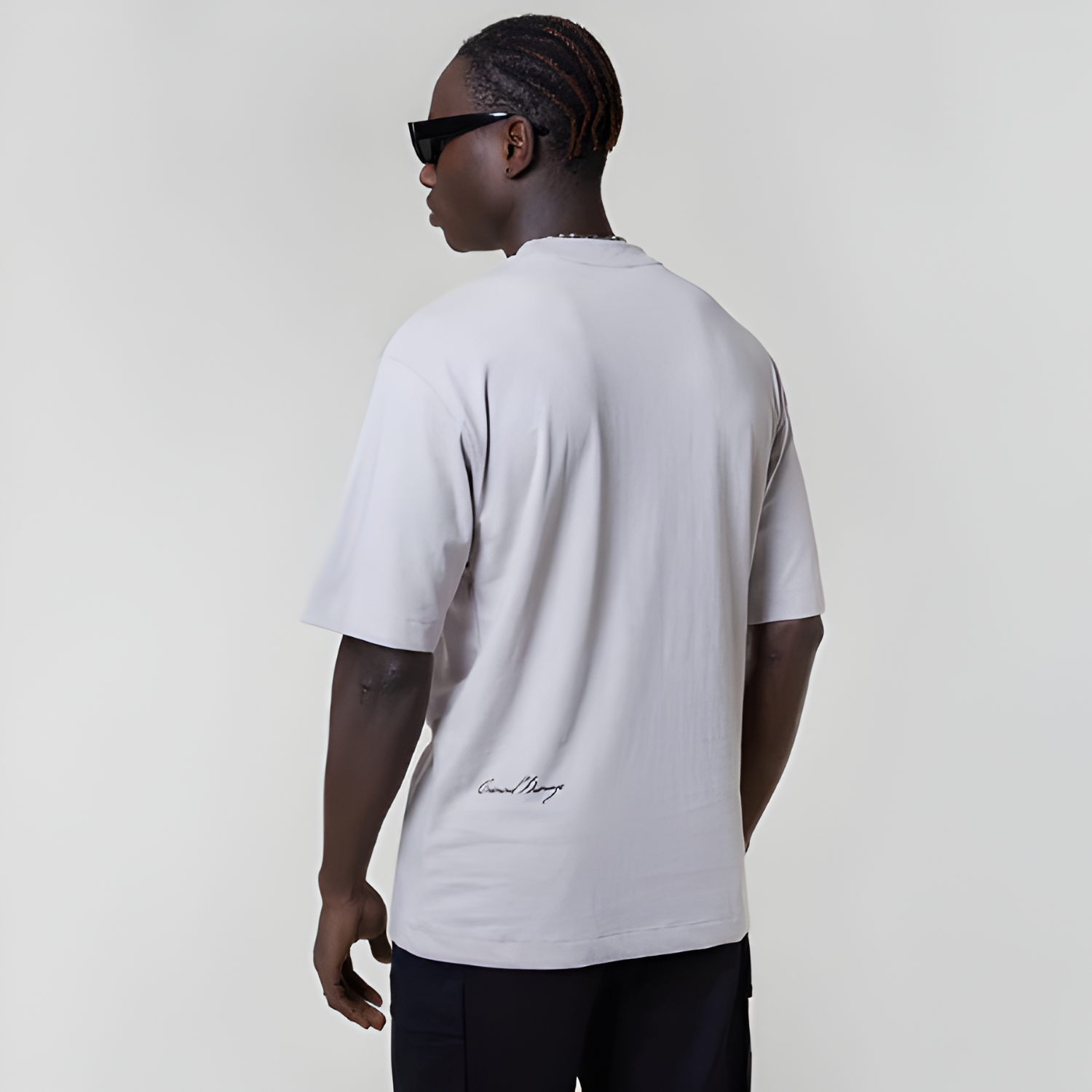 Person wearing a white t-shirt with a logo on the back against a plain background