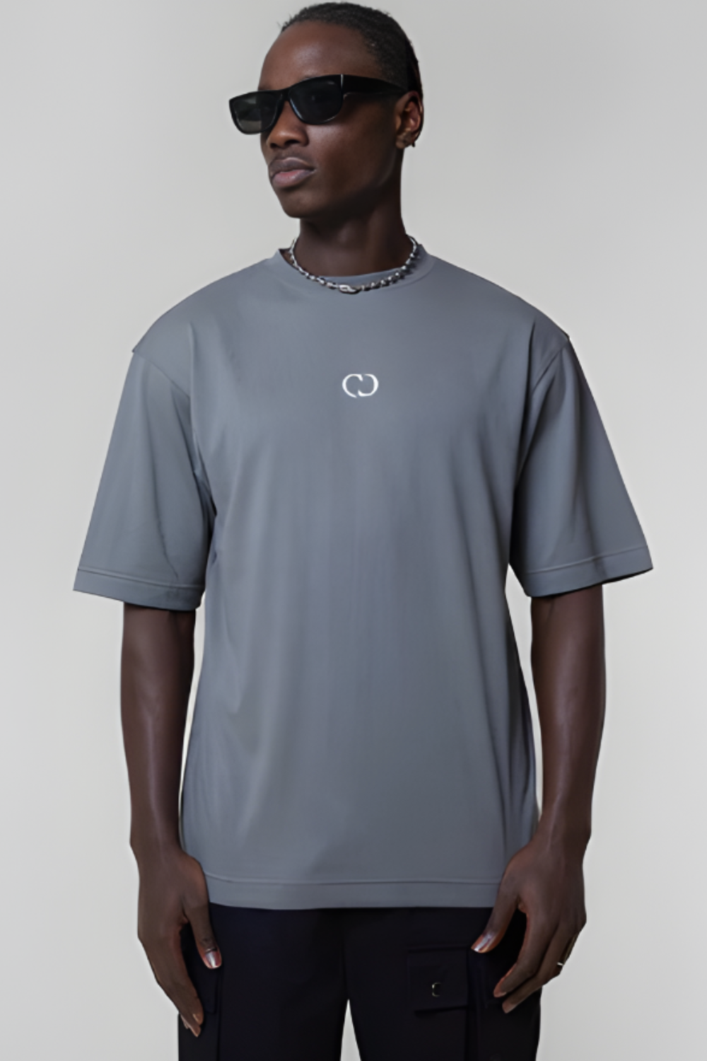 Man wearing a gray t-shirt with a logo on a plain background