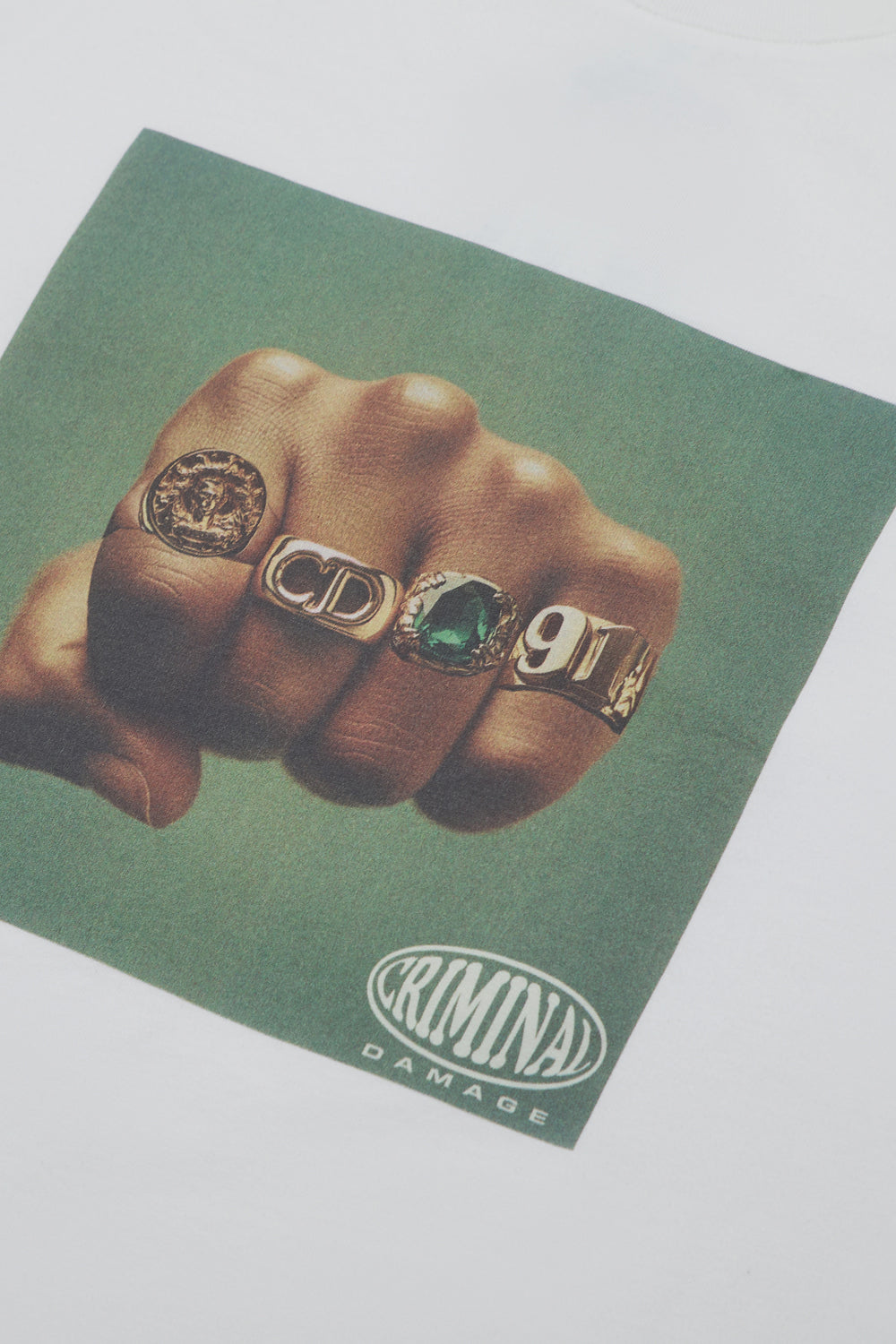 Hand with rings on a green background with 'Criminal Damage' branding.