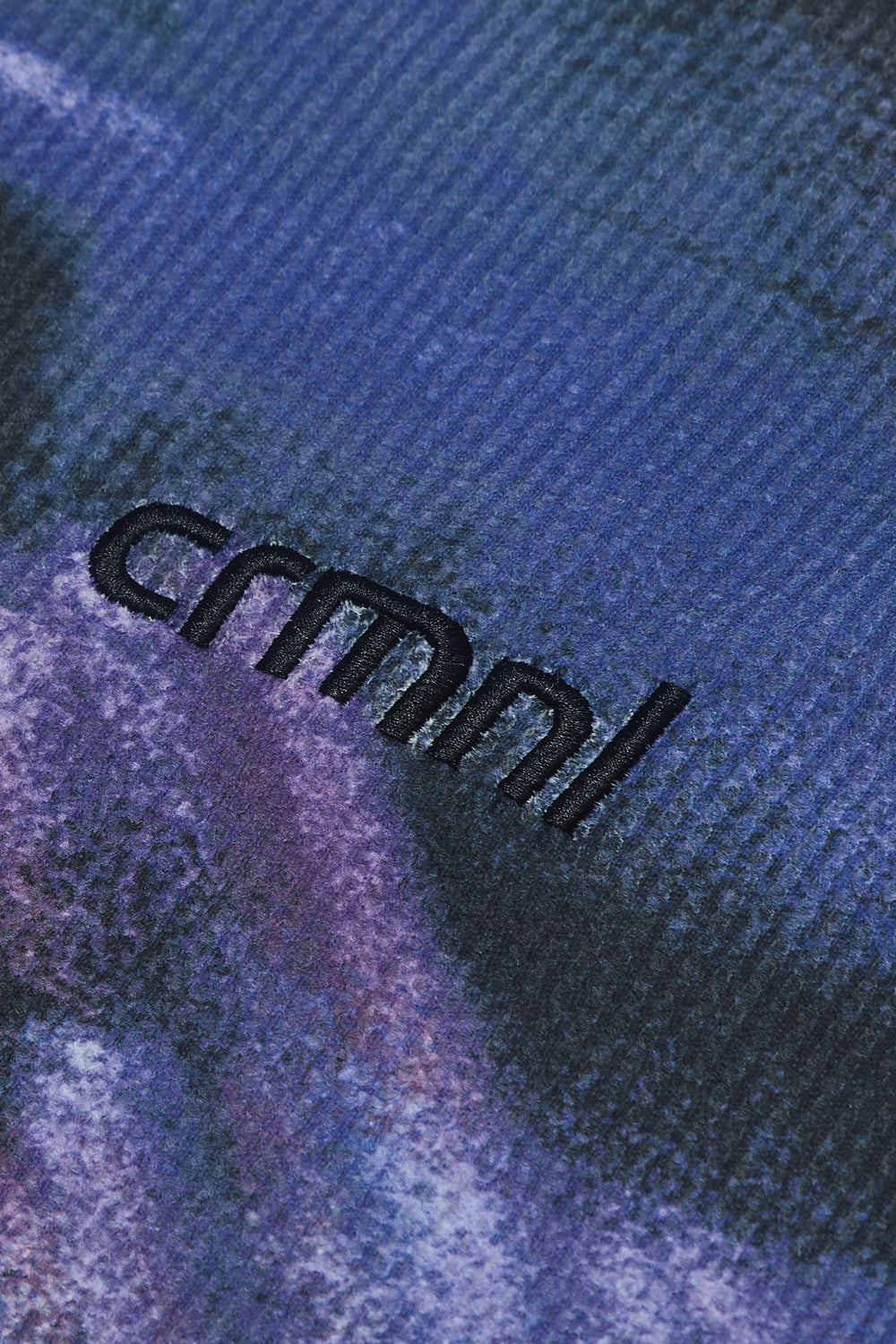 Close-up of Criminal Damage t-shirt fabric with a brand logo in the foreground