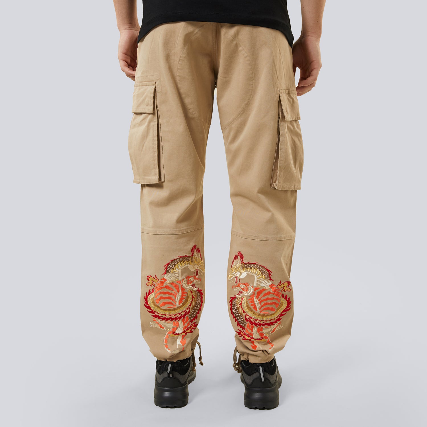 Beige cargo pants with red and gold embroidery on a white background