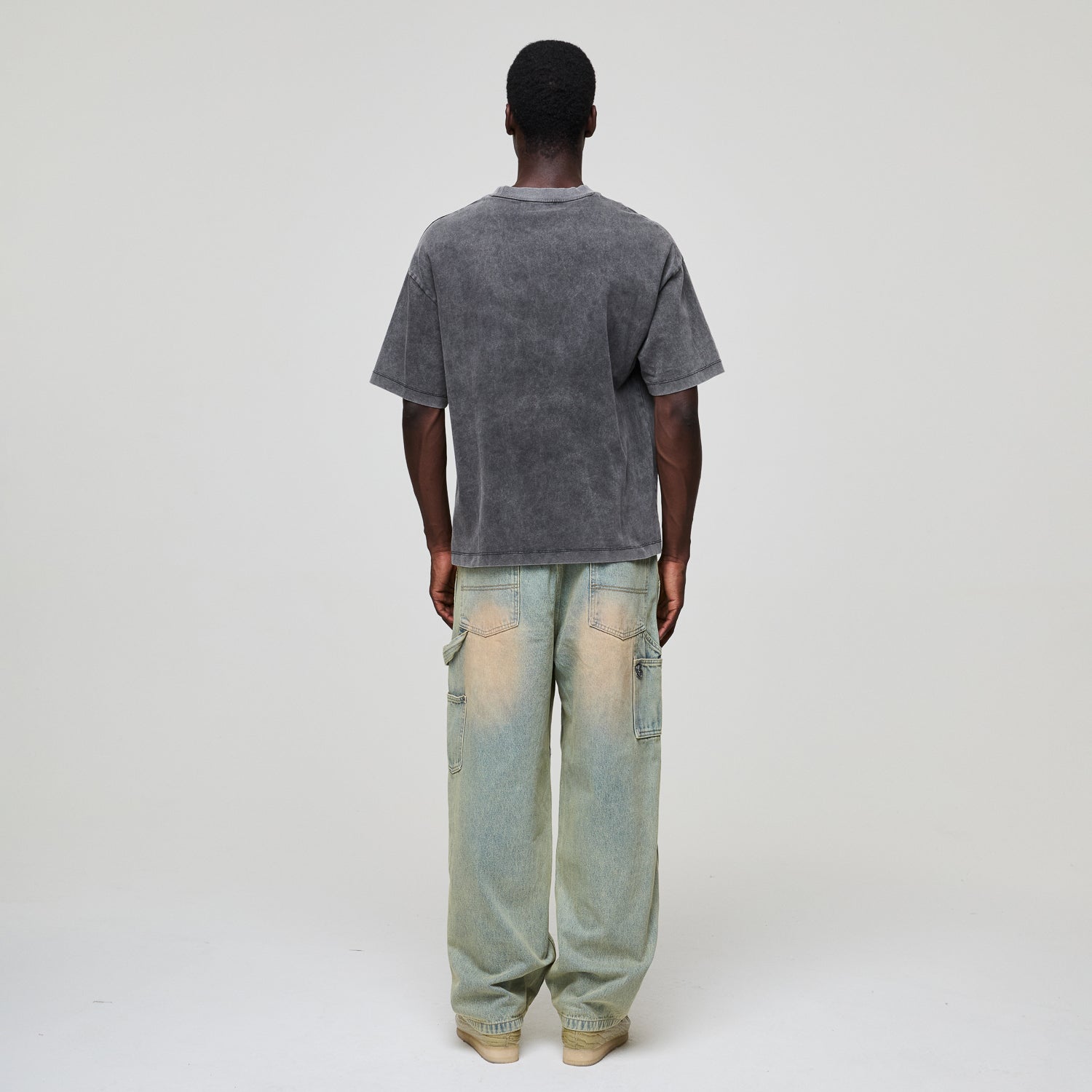 Person wearing a gray Criminal Damage t-shirt and light blue jeans on a white background