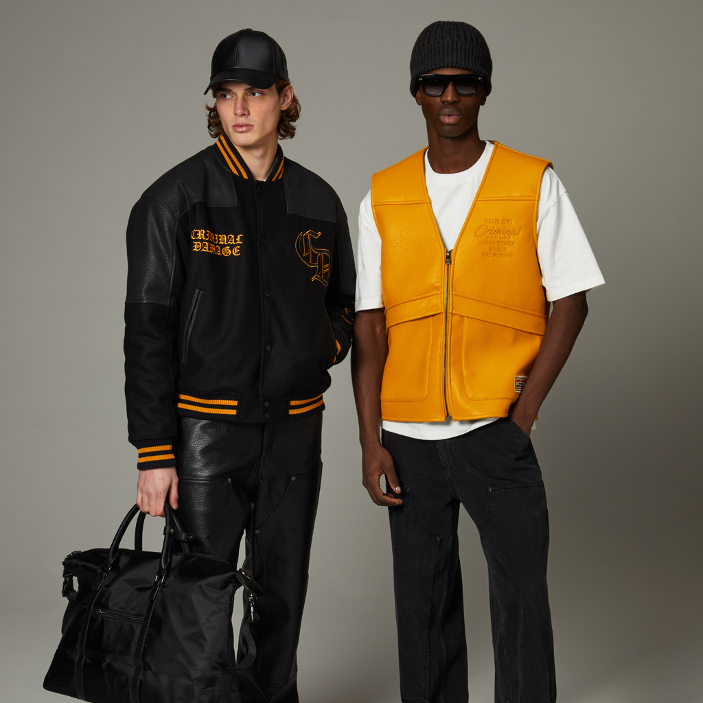 Two individuals wearing Criminal Damage stylish outfits with jackets and vests against a neutral background