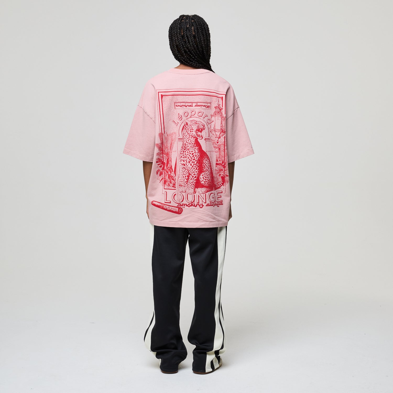 Person wearing a pink t-shirt with a graphic design on the back, standing against a plain background