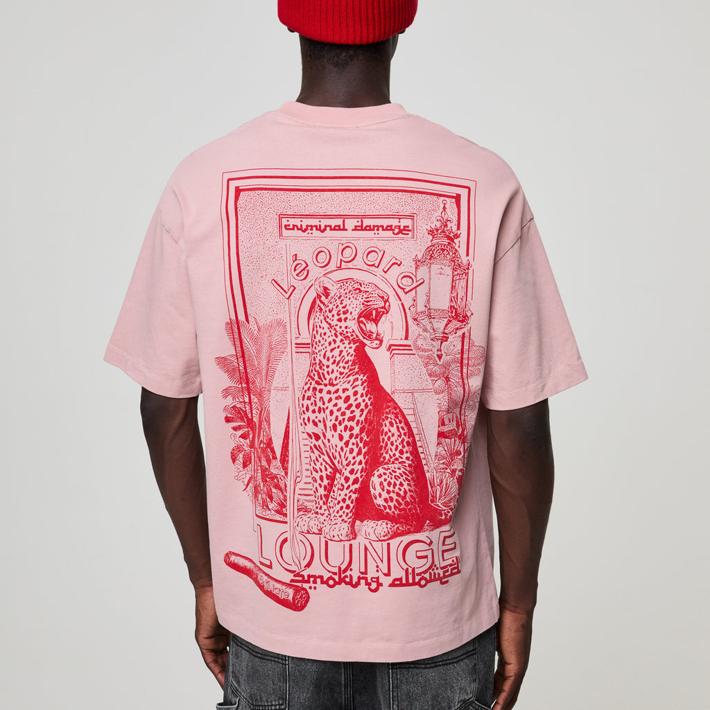 Person wearing a pink t-shirt with red graphic design on the back, featuring a leopard and text.