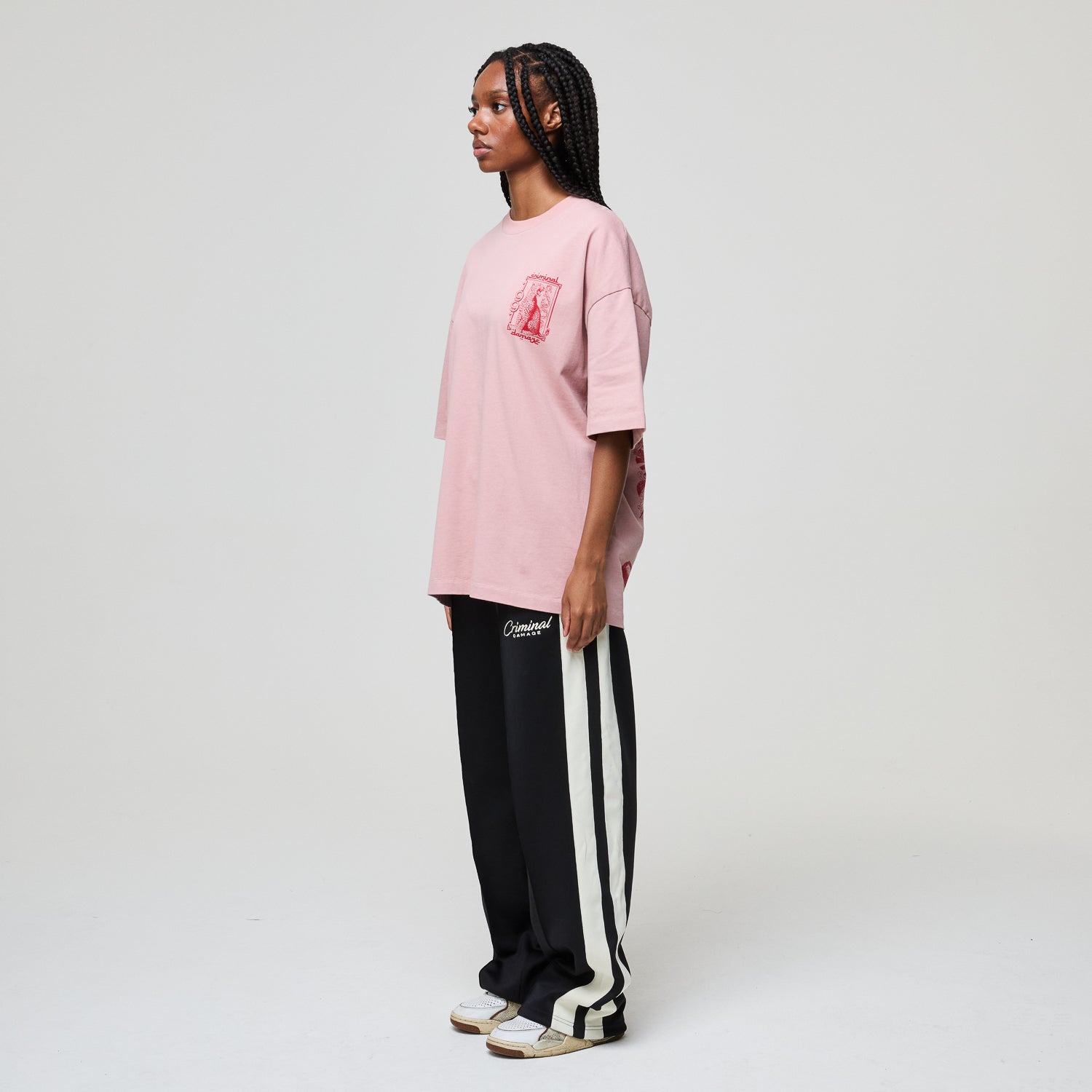 Person wearing a pink oversized t-shirt and black and white striped pants on a plain background