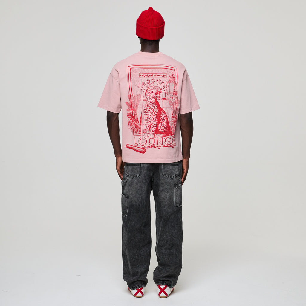Person wearing a pink t-shirt with red graphics and text, standing against a white background
