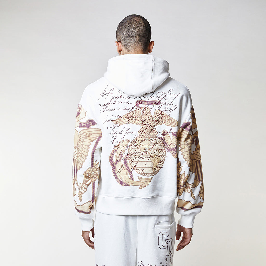 Man wearing a Criminal Damage white hoodie with graphic designs on a plain background