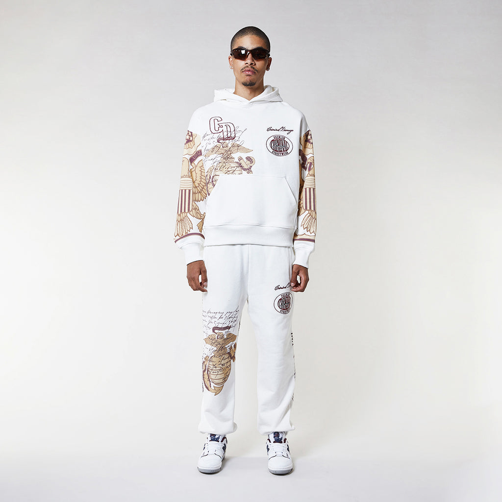 Man wearing a Criminal Damage white hoodie with graphic designs on a plain background