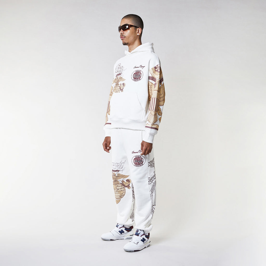 Man wearing a Criminal Damage white hoodie with graphic designs on a plain background