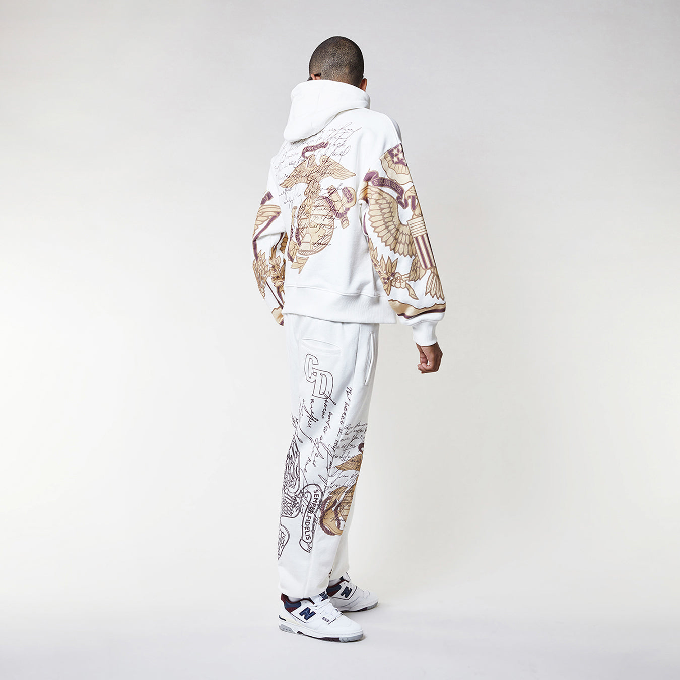 Man wearing a Criminal Damage white hoodie with graphic designs on a plain background