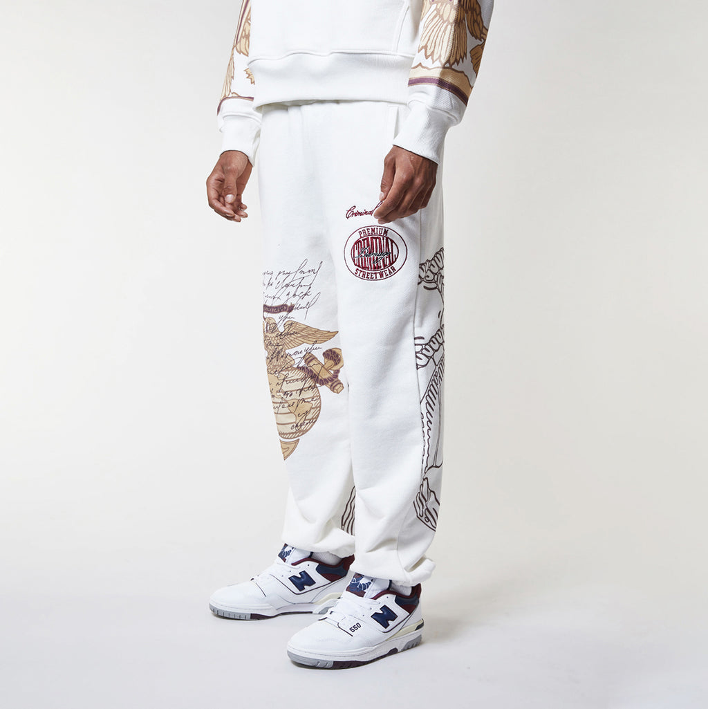 Person wearing a white sweatshirt and pants with graphic designs on a plain background