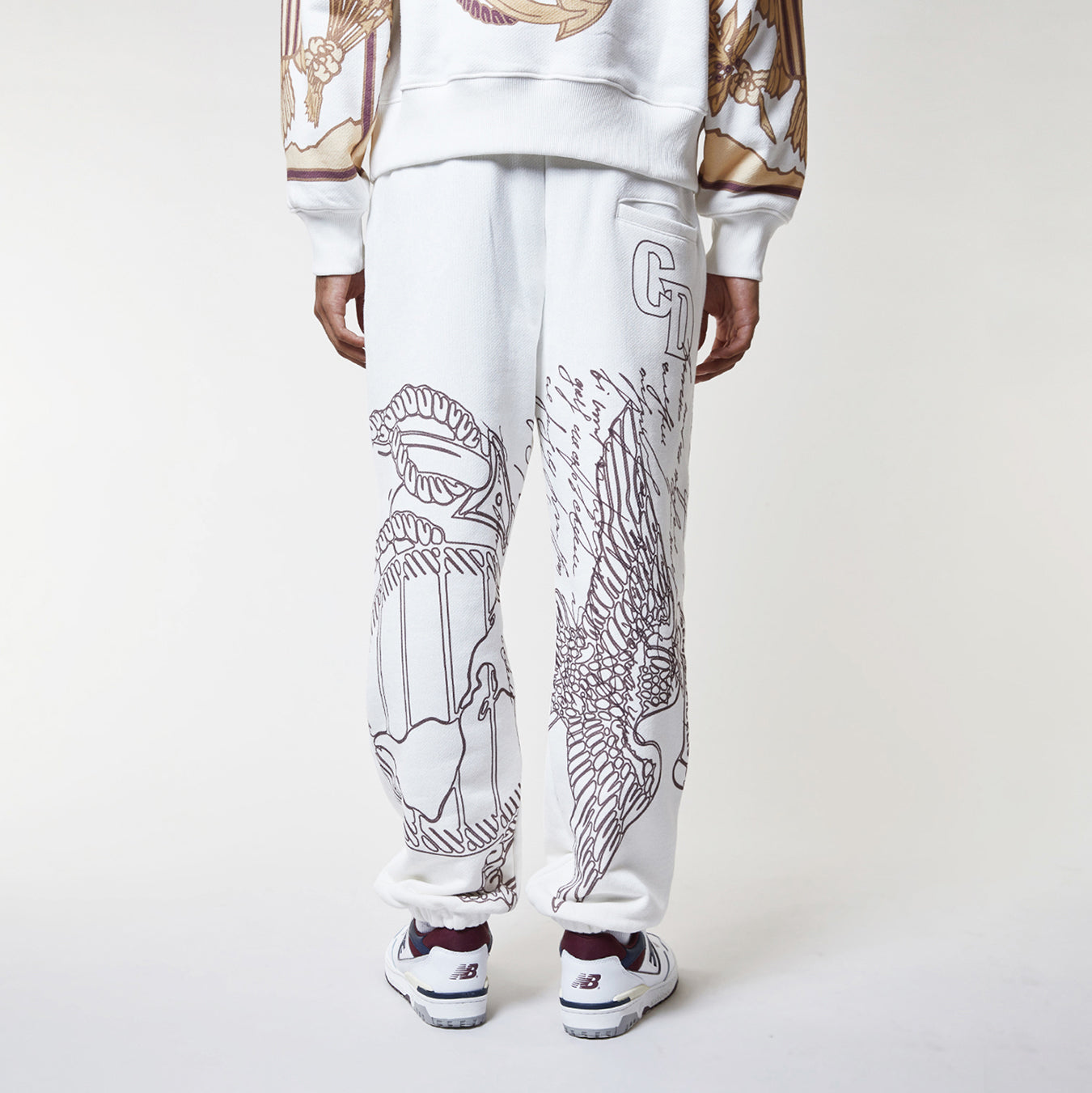 Person wearing a white outfit with black line art design on pants against a white background