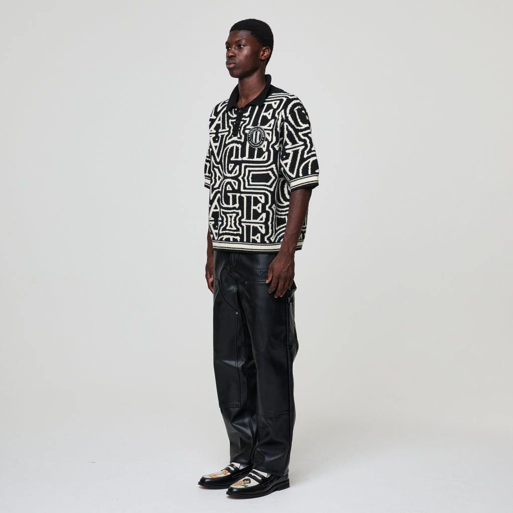 Person wearing a black and white patterned shirt with black leather pants on a white background