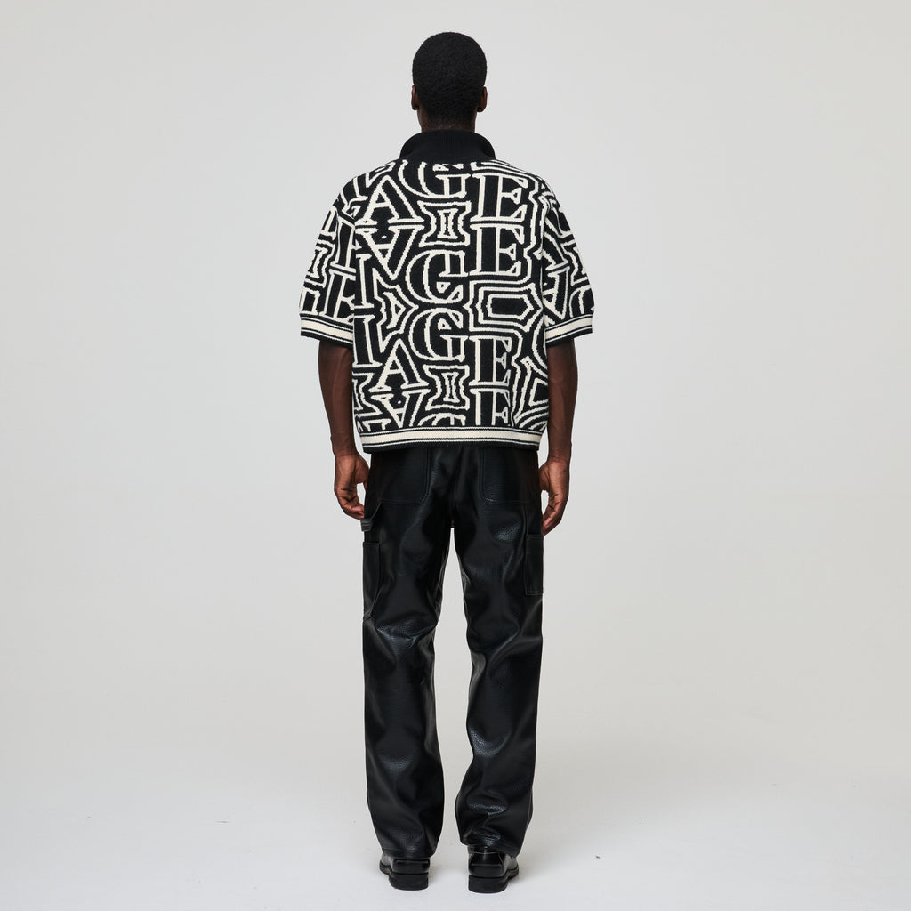 Person wearing a black and white patterned shirt with black pants on a white background