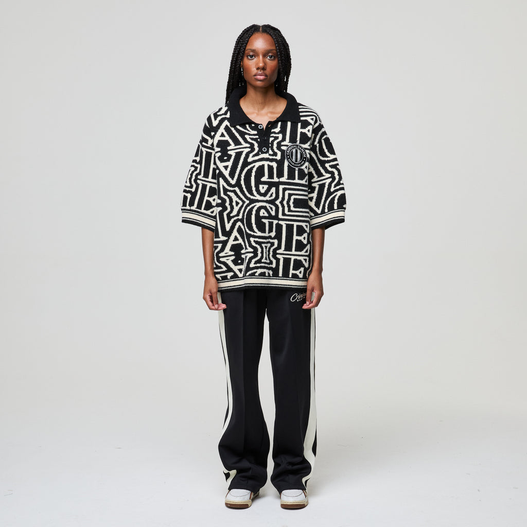 Person wearing a black and white patterned oversized shirt with black pants on a white background