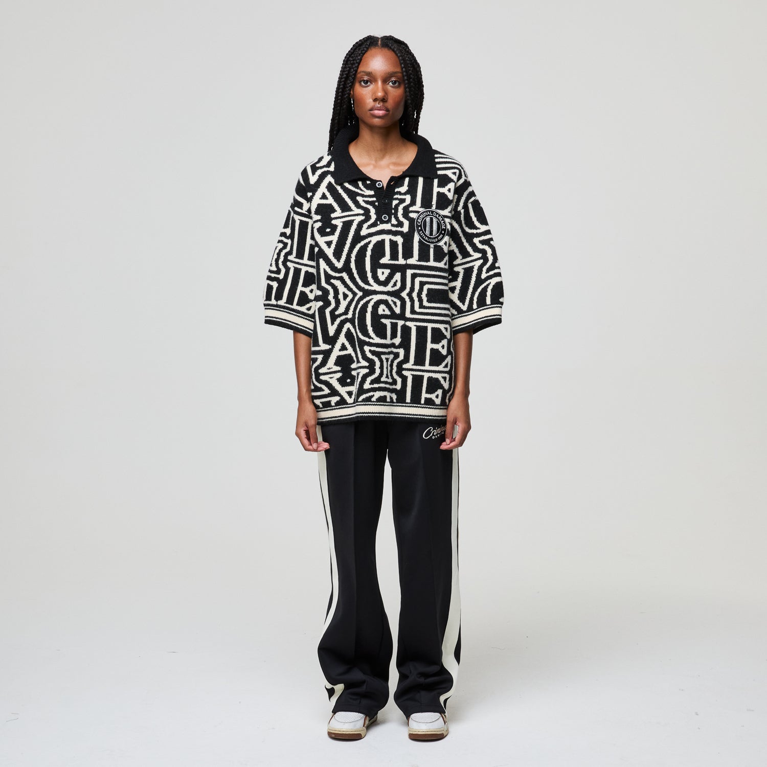 Person wearing a black and white patterned oversized shirt with black pants on a white background