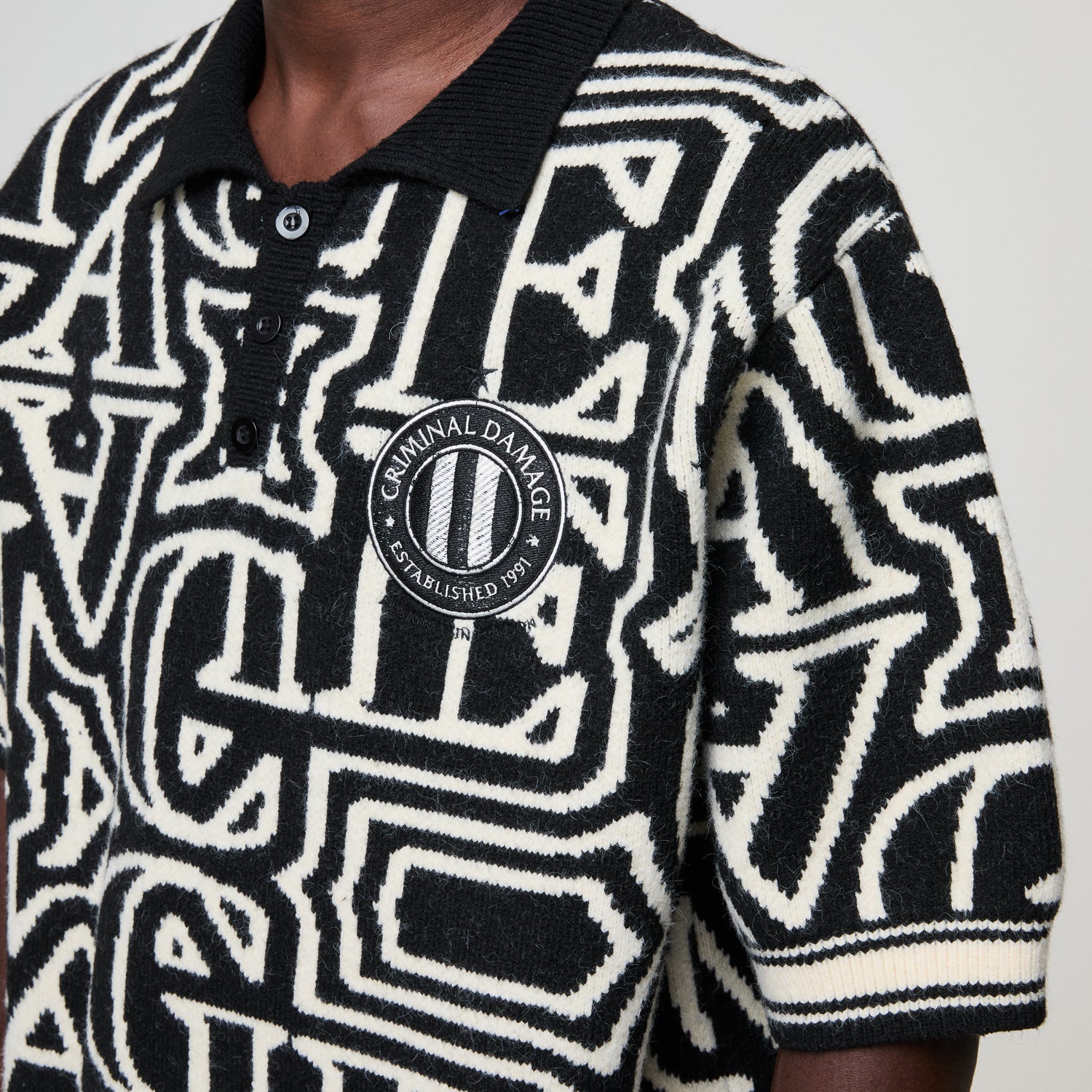 Black and white patterned sweater with a visible brand logo on a plain background