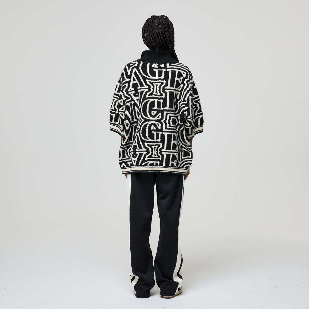Person wearing a black and white patterned jacket on a plain background