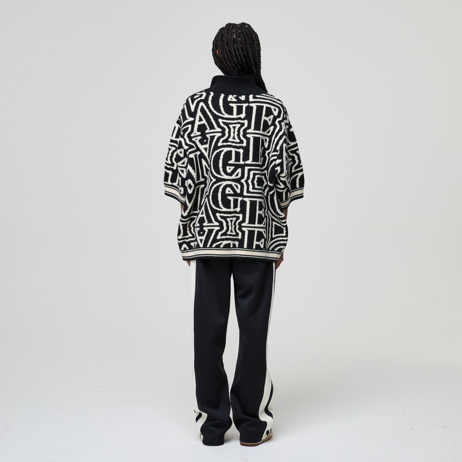 Person wearing a black and white patterned jacket on a plain background