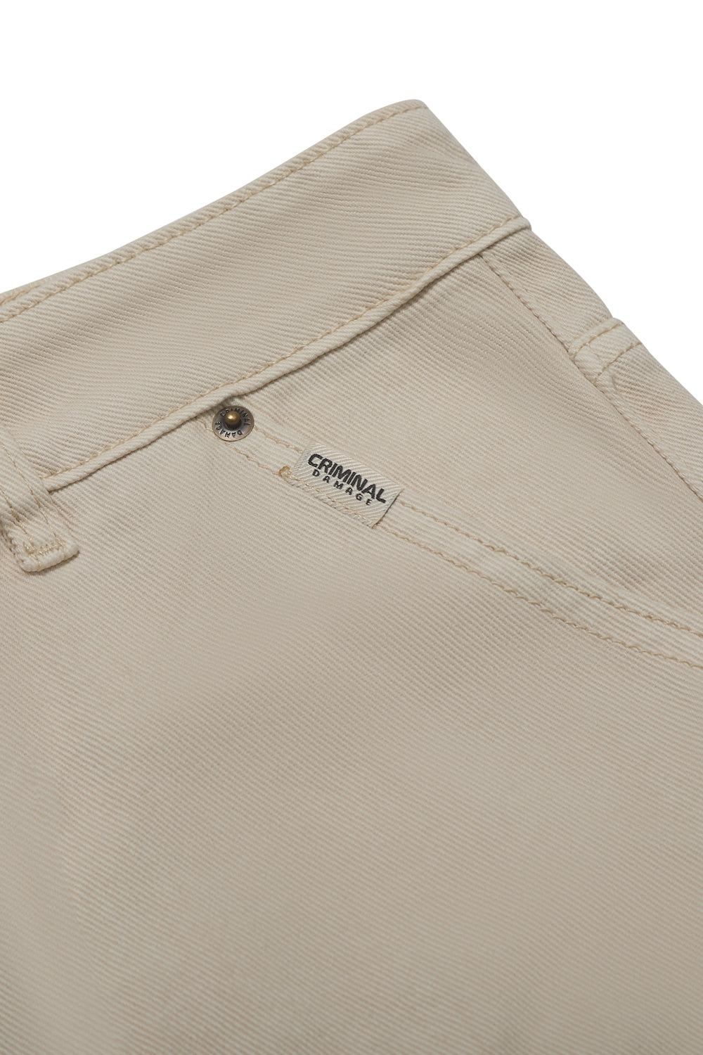Close up of Criminal Damage shorts with brand label on white background