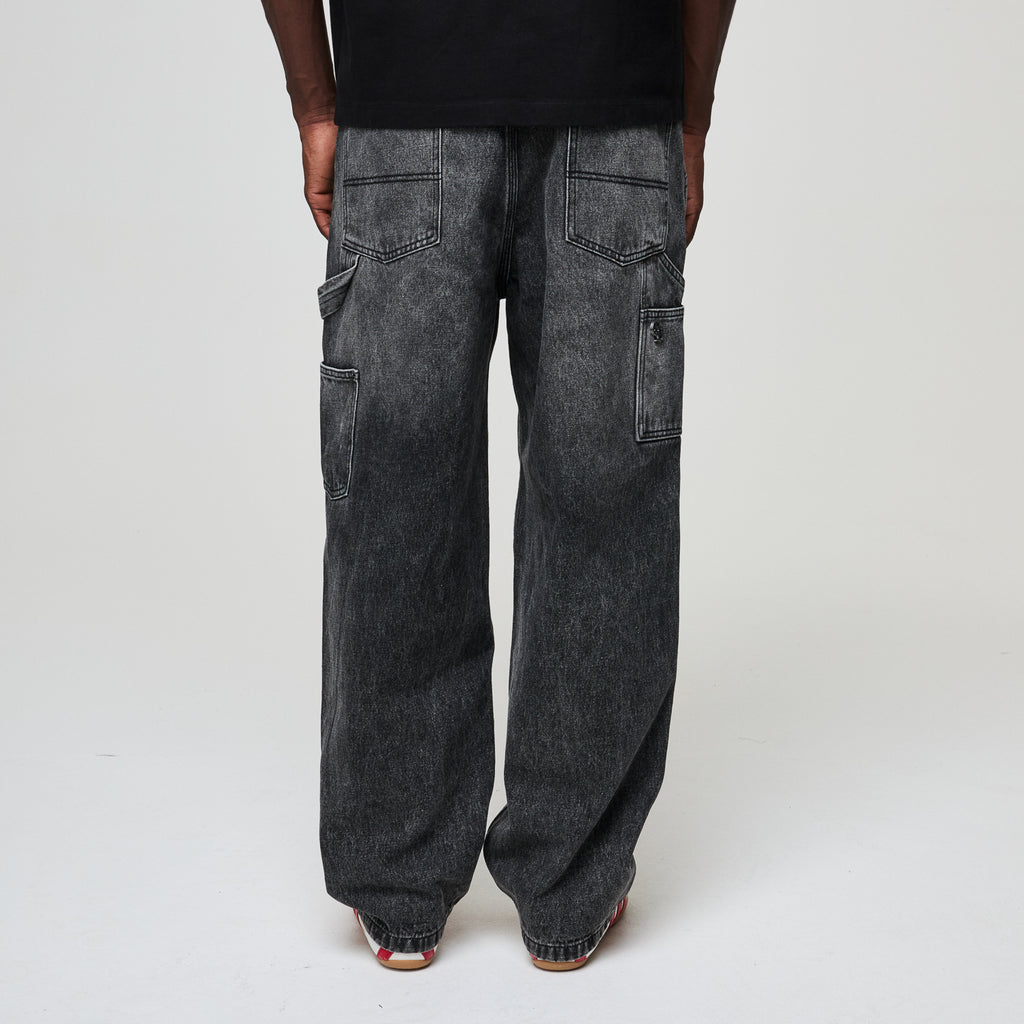 Person wearing black wide-leg jeans on a plain background