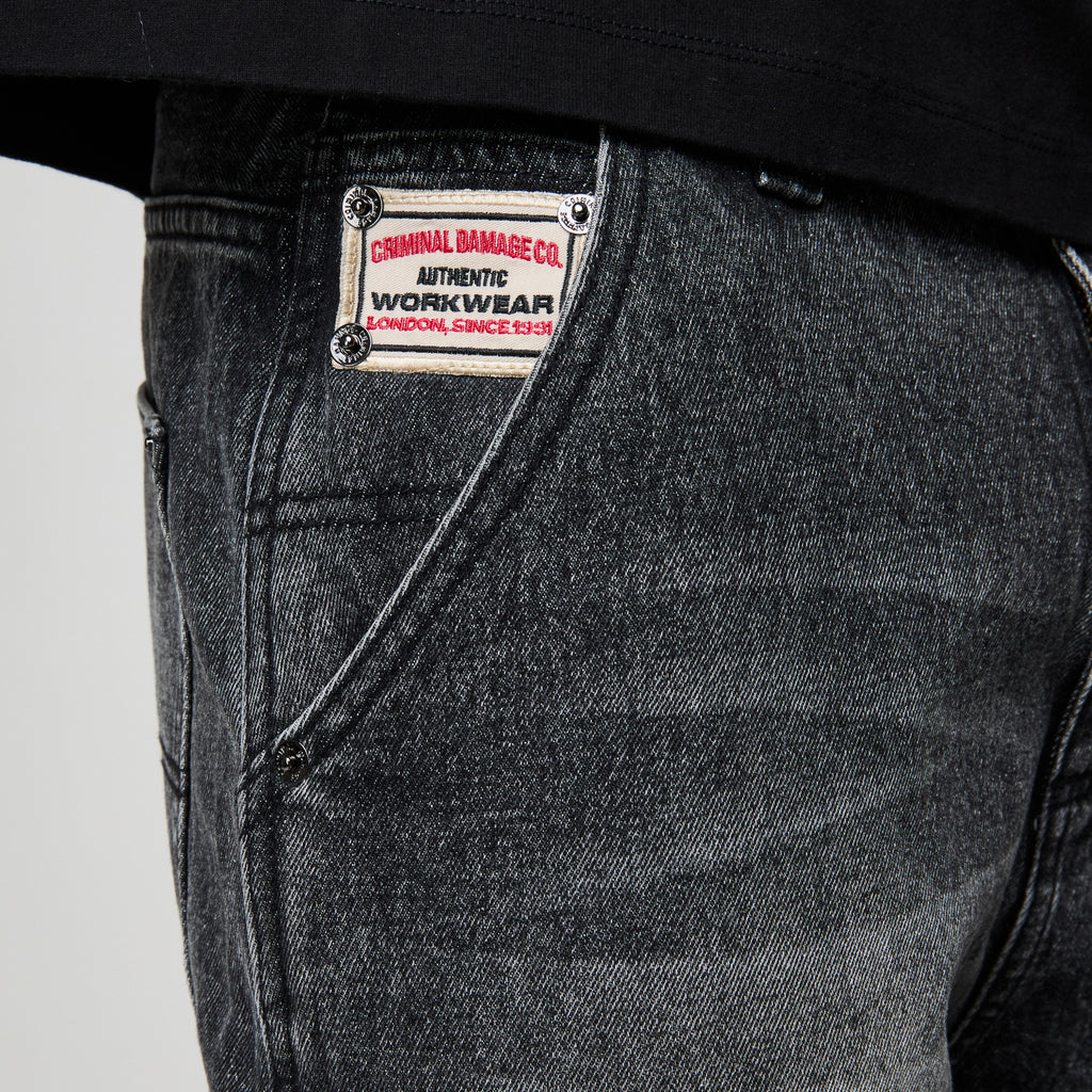Close-up of a denim jacket with a brand label on a plain background