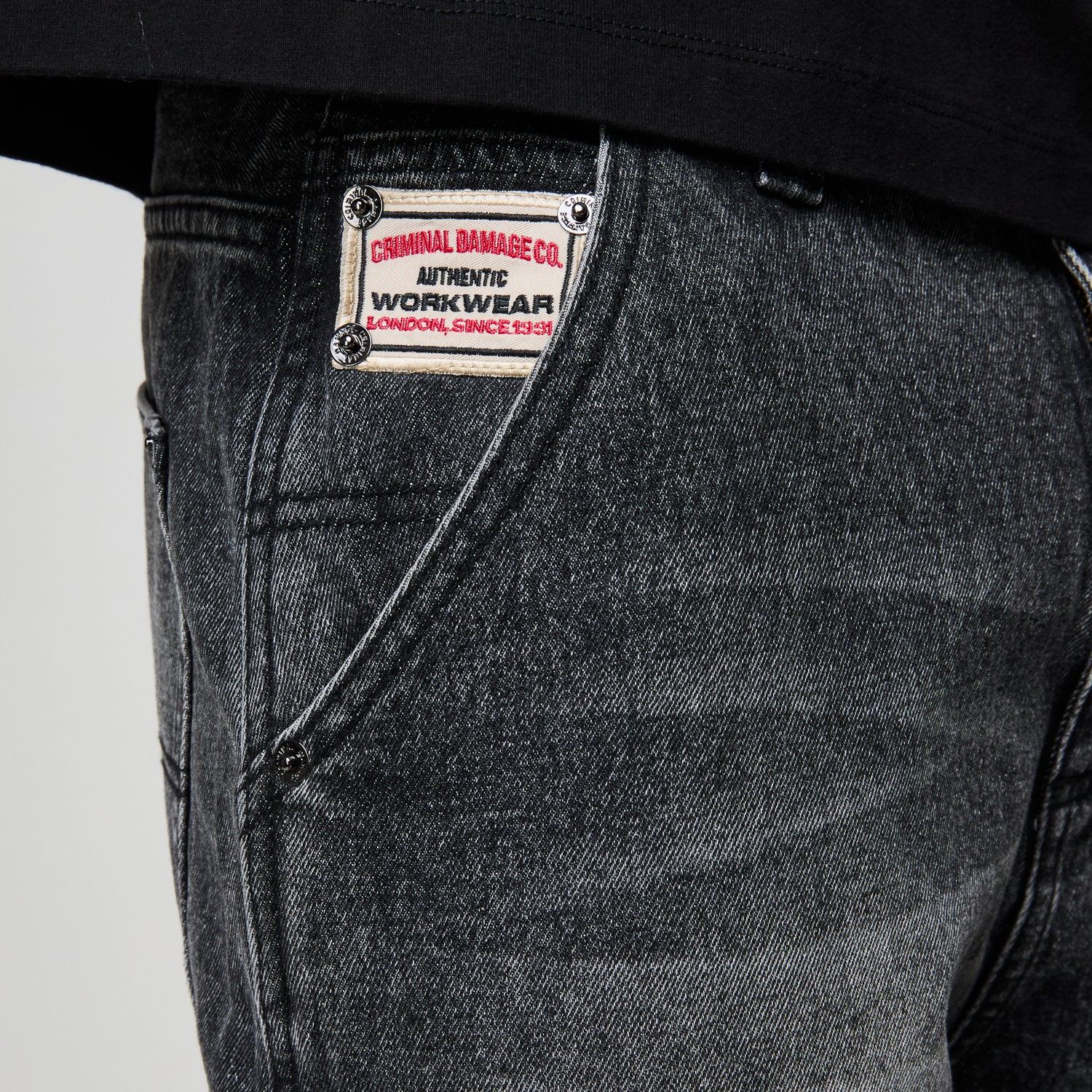 Close-up of a denim jacket with a brand label on a plain background